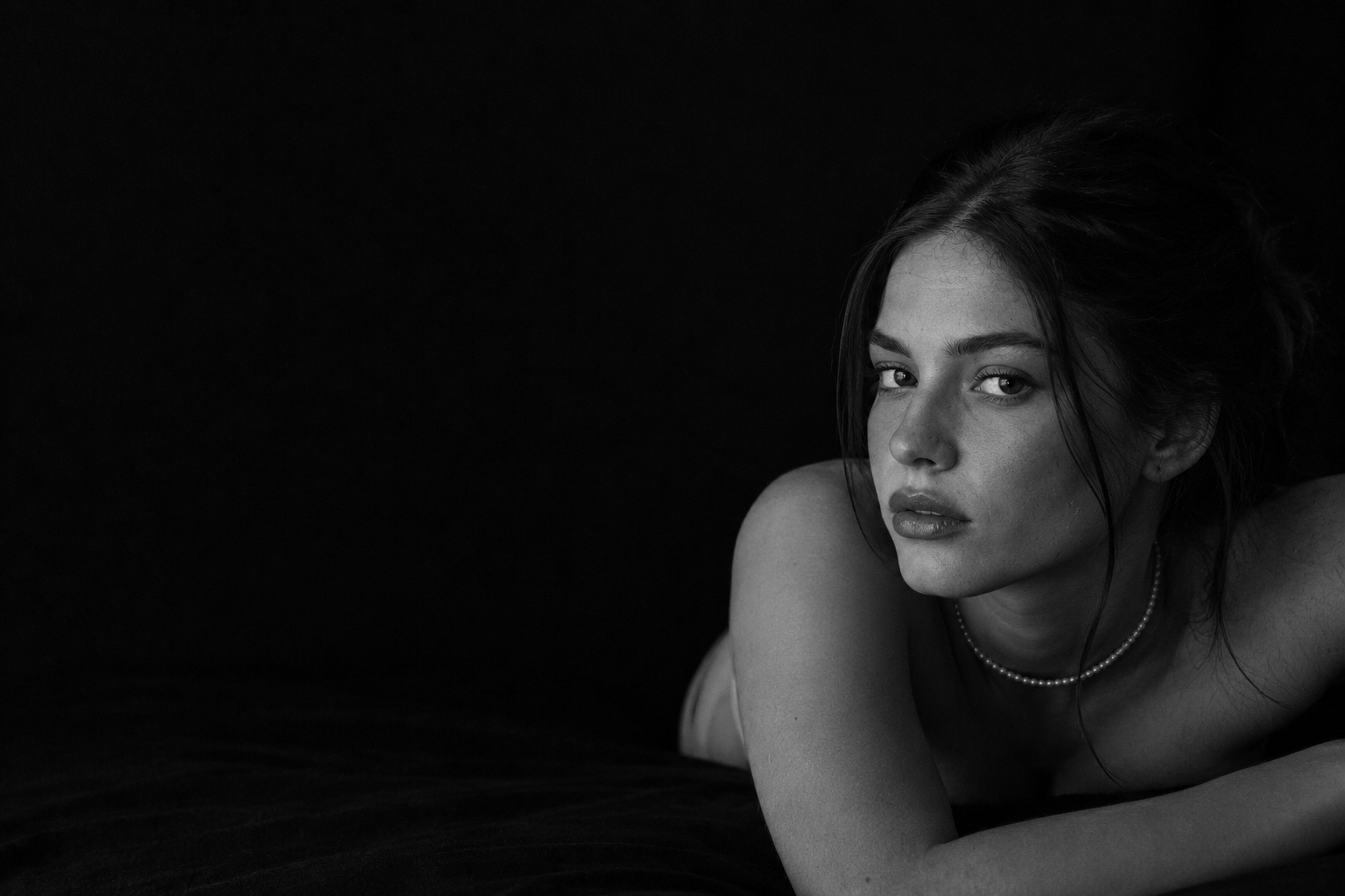 Retrato en blanco y negro de una mujer recostada, mirando a cámara